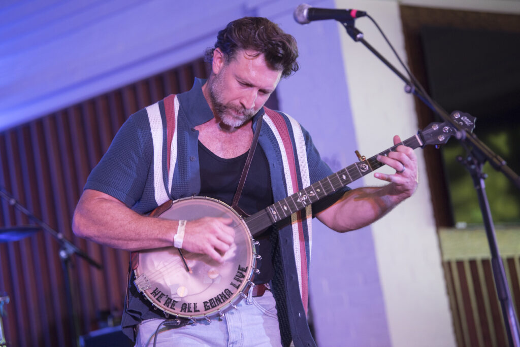 Tony Kamel plays his banjo on stage.